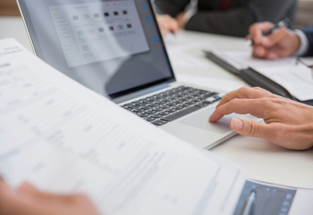 person typing on computer with paperwork