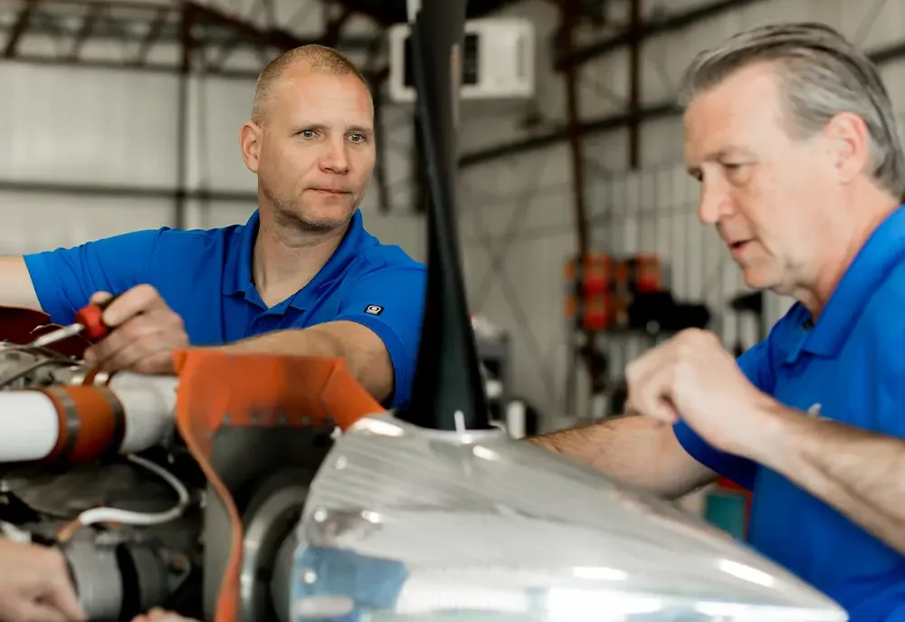 two Lone Mountain mechanics working on engine