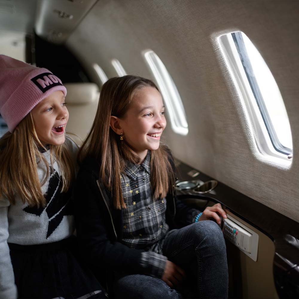 Two younger girls in private plane staring out window