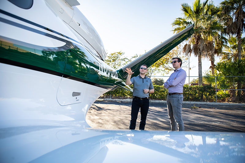 Two people talking next to private plane